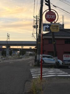 交差点の角に立つ赤い消火栓の標識と、「ニイガタベース ここで右へ」の道案内サイン。