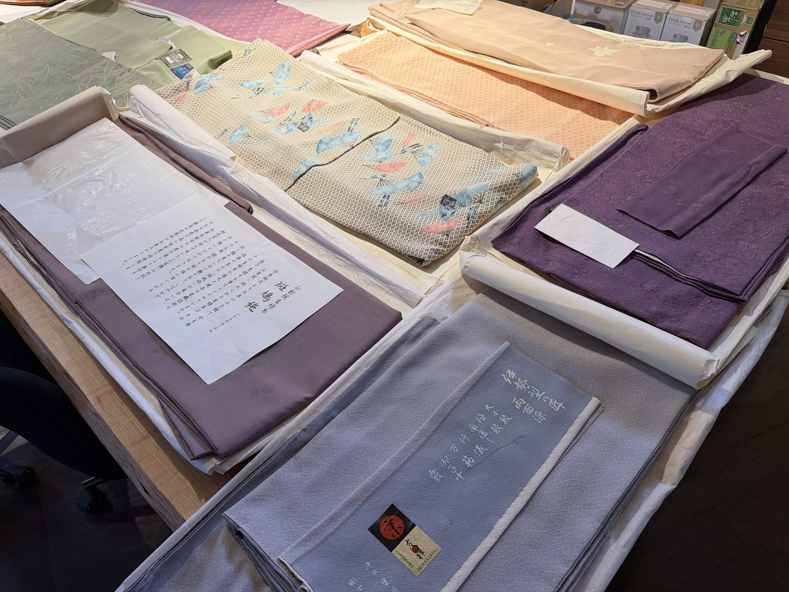 箱に整理された着物や帯。品質表示の証紙が付いた一枚もある、会場の着物の様子
