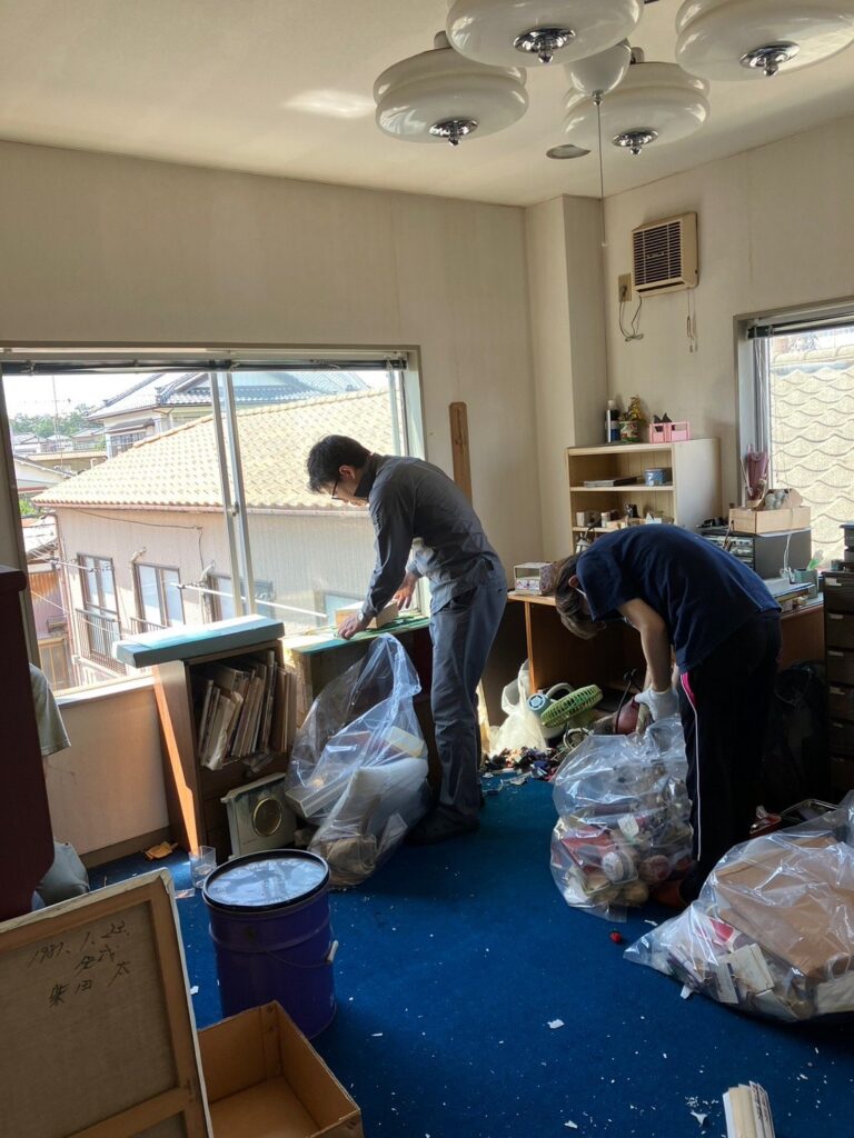 室内で袋詰めした家財を整理する作業員。