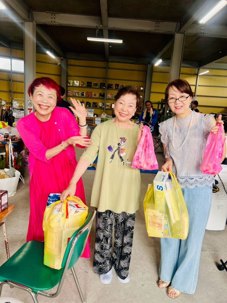 たくさんの買い物袋を手に、笑顔で並ぶ来場者3人。