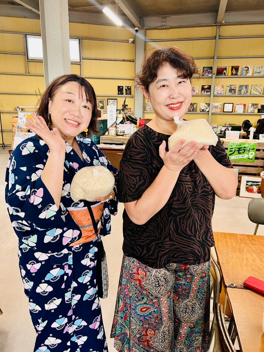 浴衣姿の来場者ふたりが、手にした品物を見せて笑顔でポーズをとっている。