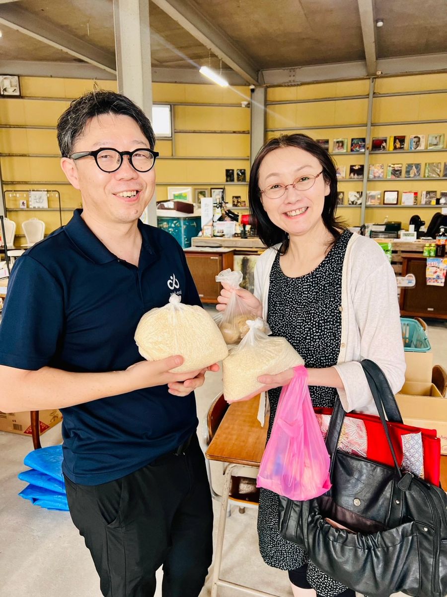 来場者ふたりが、ぬいぐるみと買い物袋を手に笑顔でポーズをとっている。