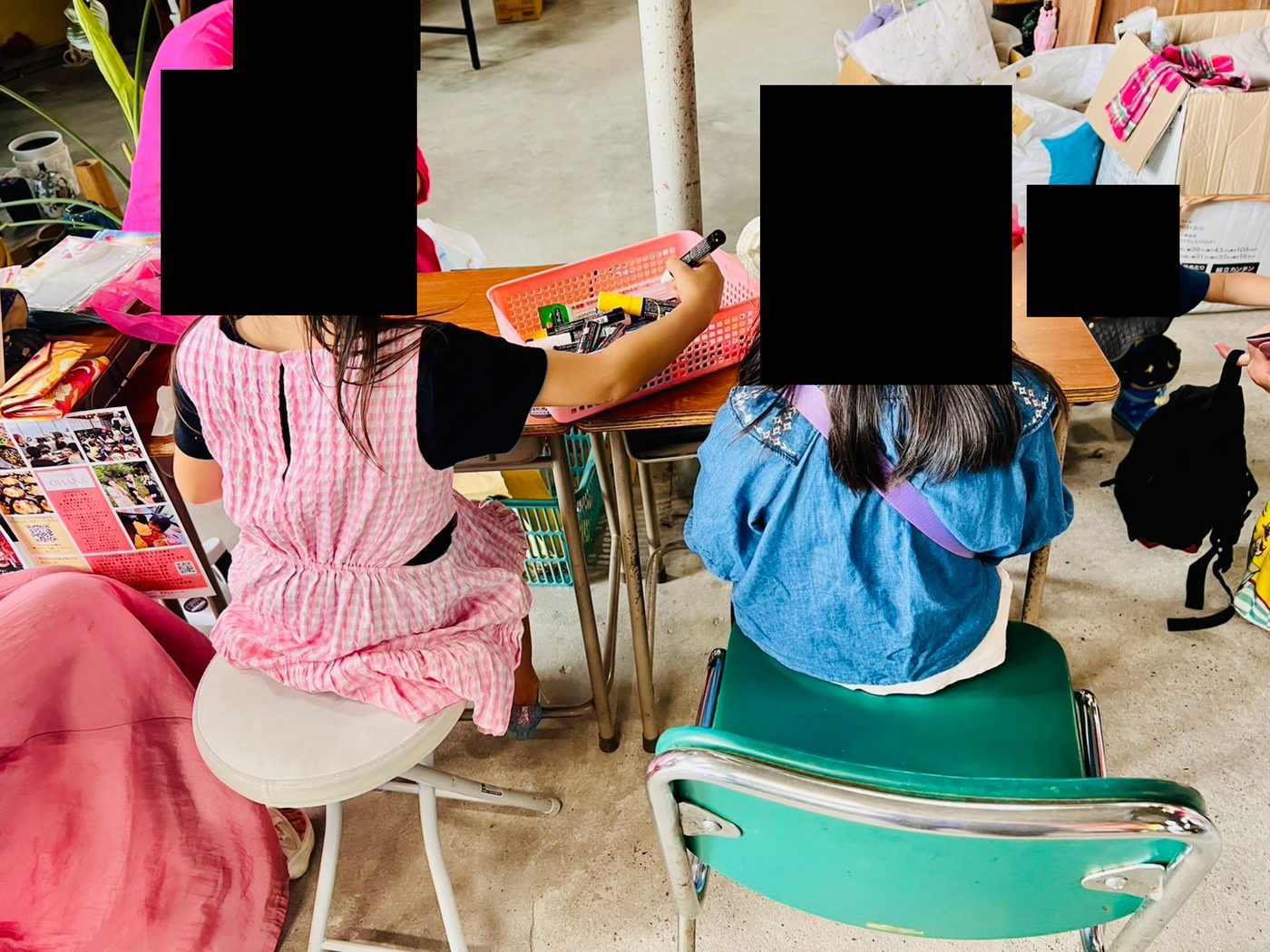 テーブルに向かって、子どもたちがペンの入ったかごを囲み、カードに書き込んでいる様子。