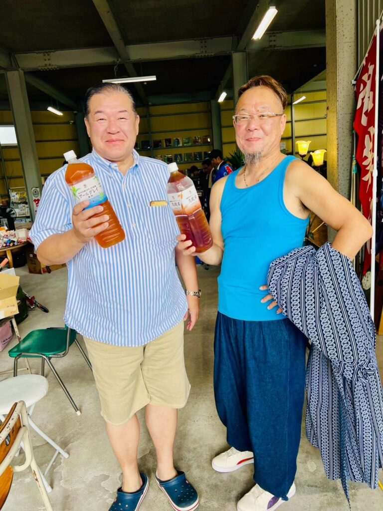 品物を手にした男性2人が並んで立っている。