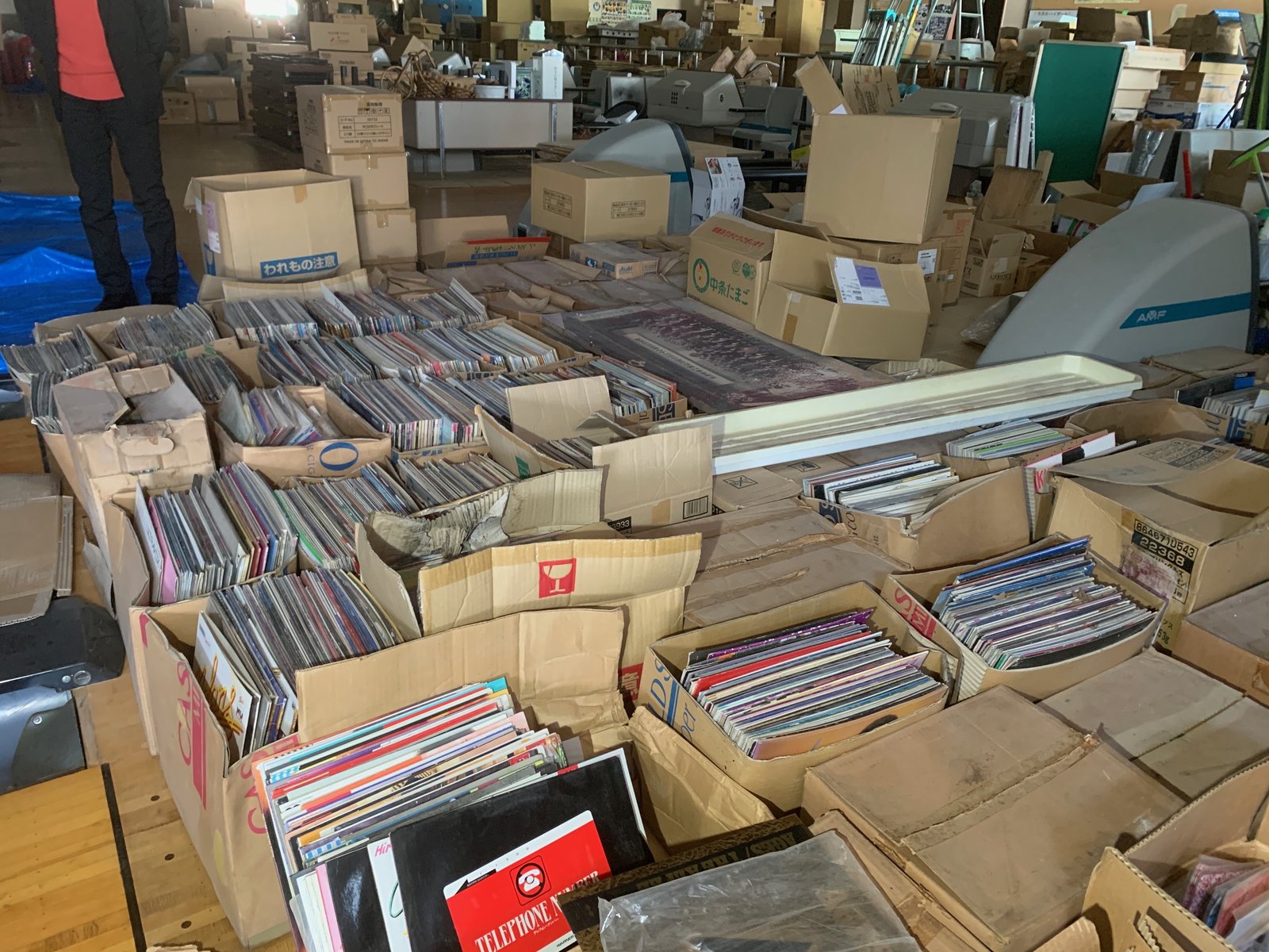 廃業したボウリング場の館内で、段ボール箱いっぱいに詰められた大量のレコードが何十箱も並んでいる様子。