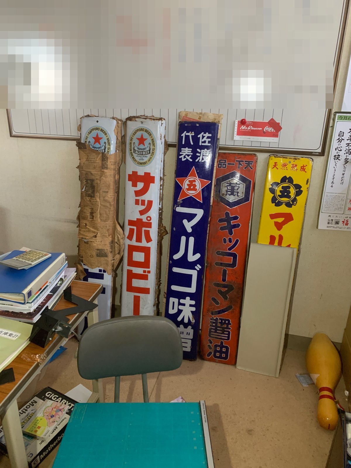 事務所に立てかけられた古いホーロー看板。キッコーマン醤油、「佐渡代表」と書かれたマルコ味噌、大日本麦酒時代のサッポロビールの看板が並ぶ。