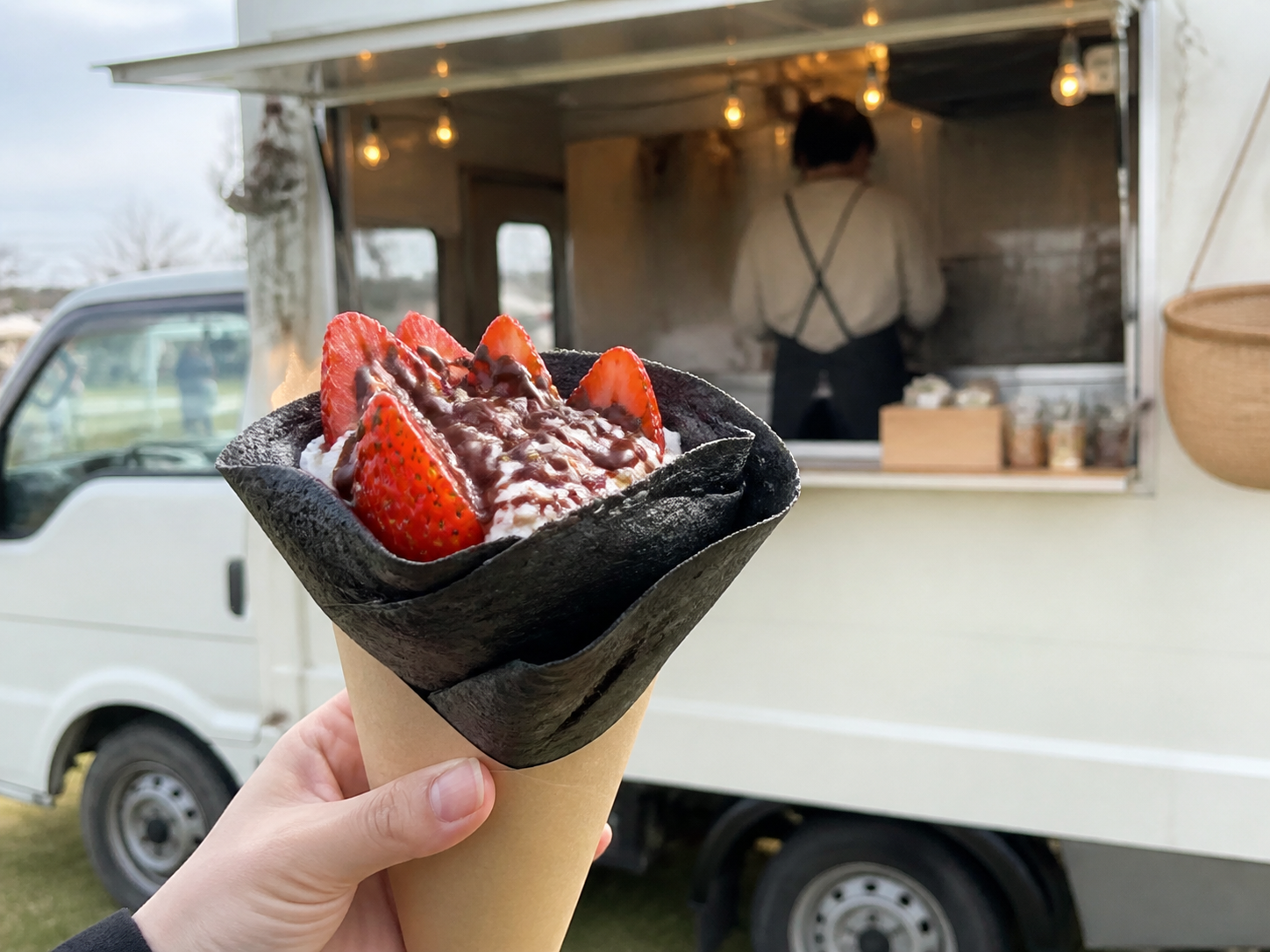 キッチンカーの前で持つ黒いクレープ