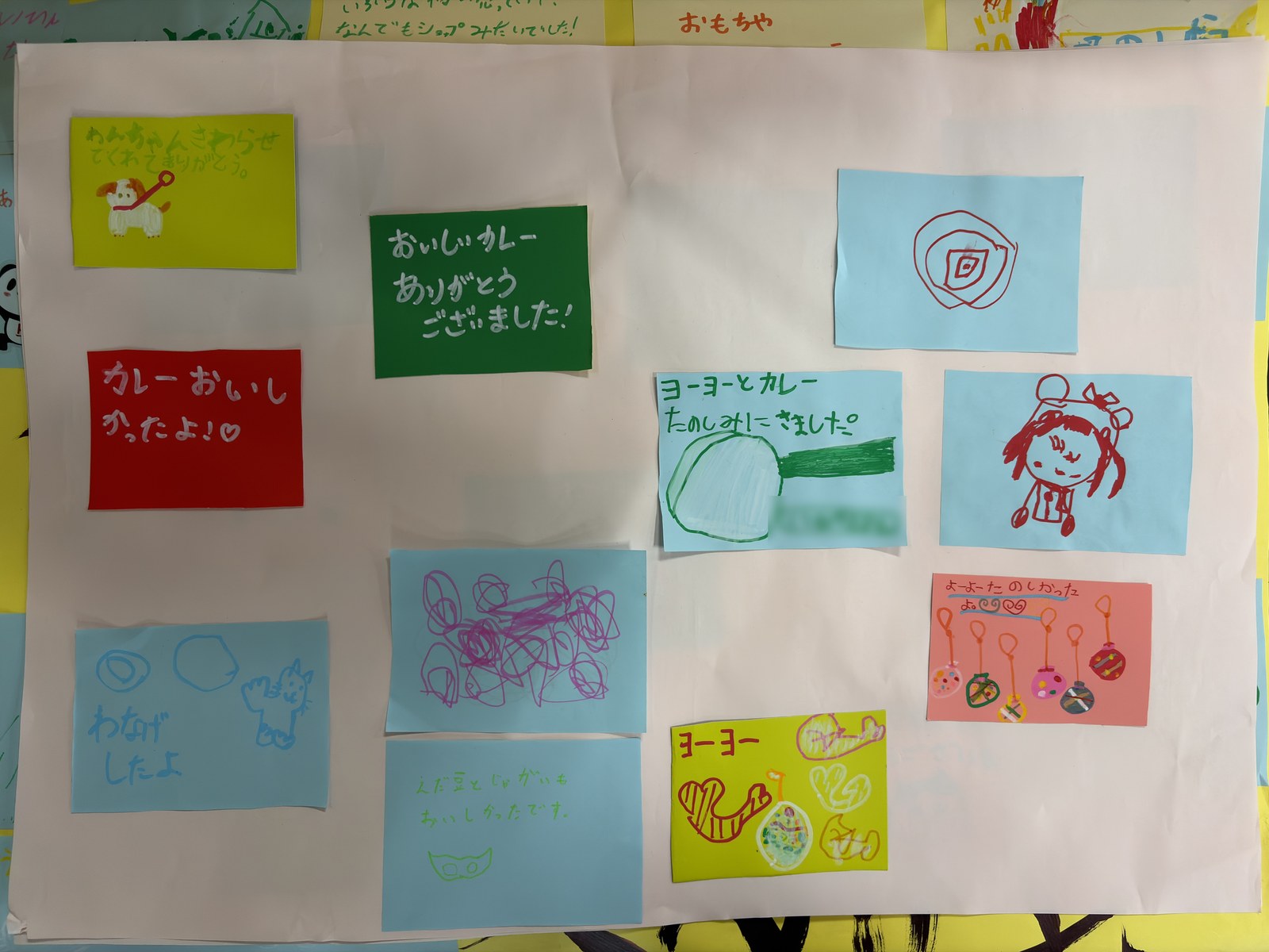 白い模造紙に、子どもたちが色紙に書いたメッセージと絵が貼られた寄せ書き。「おいしいカレーありがとうございました!」「わなげしたよ」「よーよーたのしかったよ」などの言葉が並ぶ。