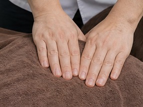 施術者の両手が、うつぶせになった人の背中にそっと添えられている。