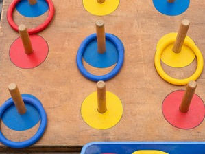 木の板に立てた棒へ、赤・青・黄の輪が掛かっている輪投げの台。