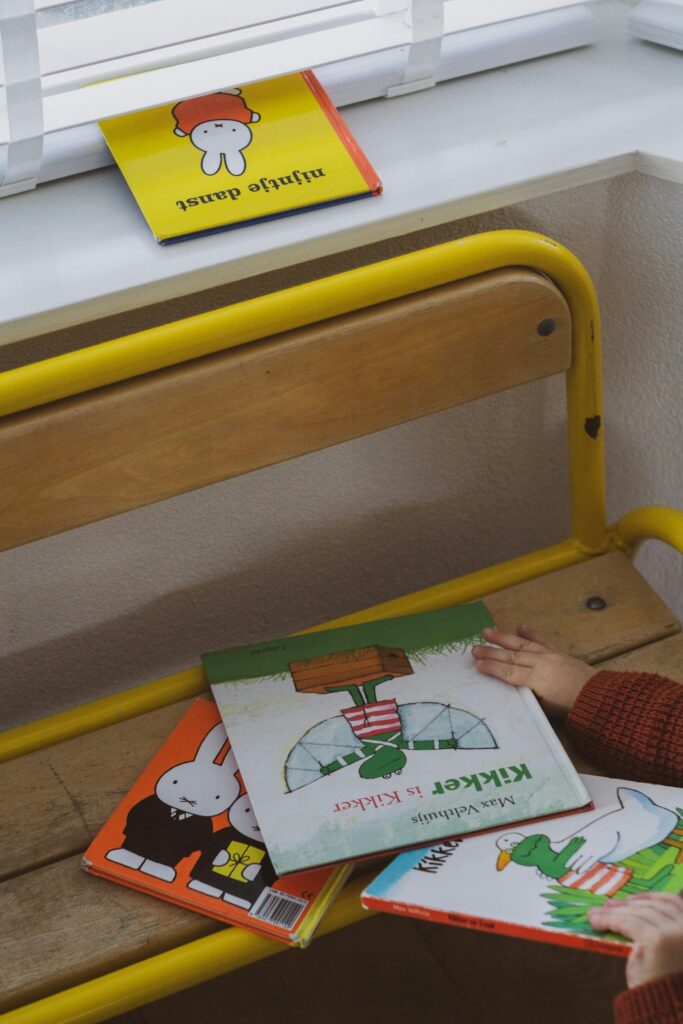 黄色い椅子の上や窓辺に置かれた、数冊の子ども向け絵本。