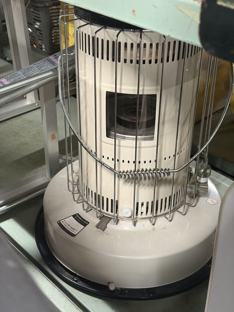 ガードの付いた、白い丸型の石油ストーブ。