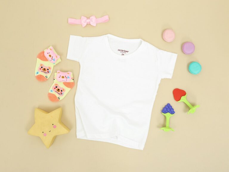 ベージュの台の上に、子ども用の白いTシャツと動物柄の靴下、小さなおもちゃが並べてある。