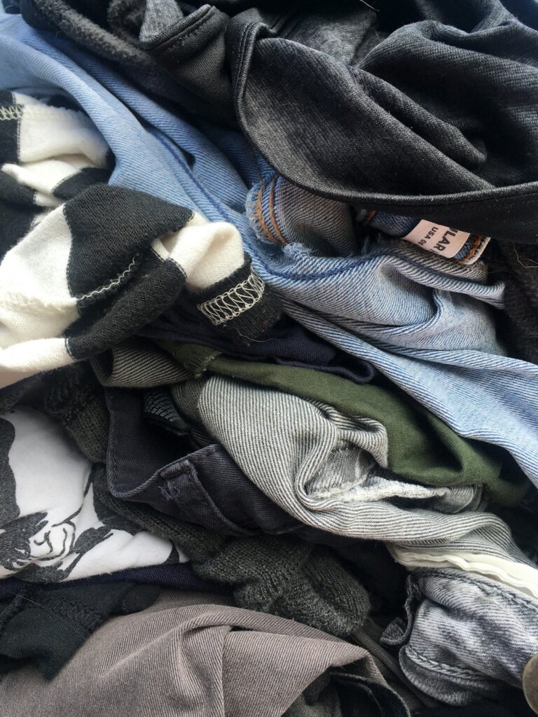 デニムやシャツ、ボーダーのTシャツなど、着古した服が重なった山。