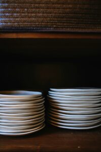 棚に積み重ねられた、白い無地の皿。（イメージ）