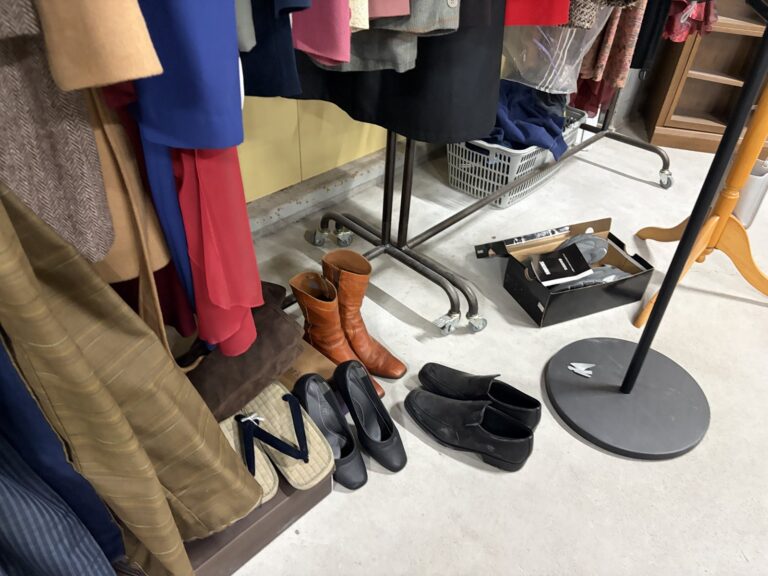 服のラックの下に、ブーツやパンプス、革靴、下駄が並んでいる。