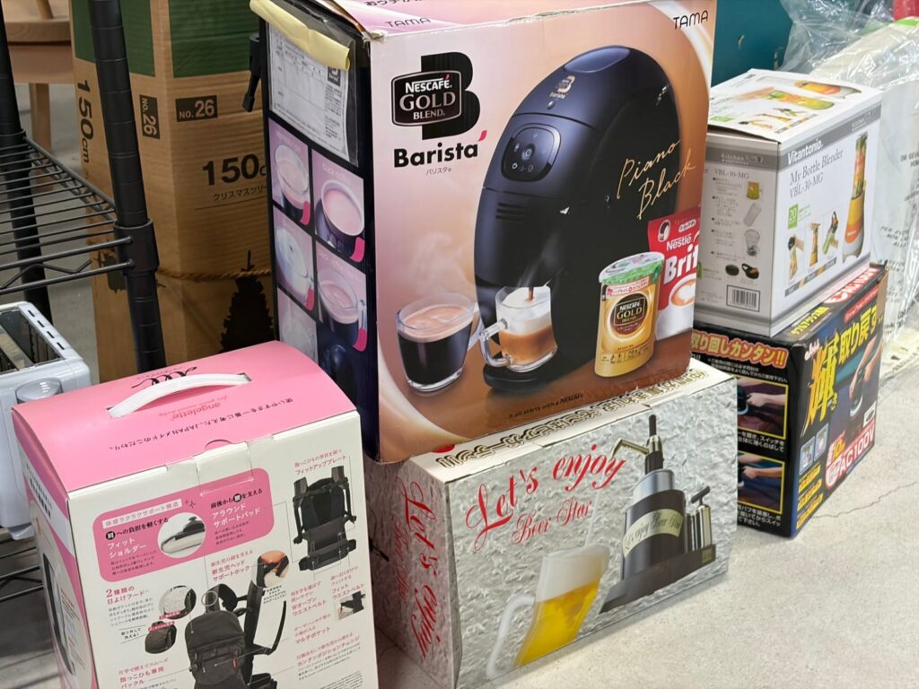 コーヒーメーカーやブレンダー、ビールサーバーなど、箱に入ったままの家電が積まれている。