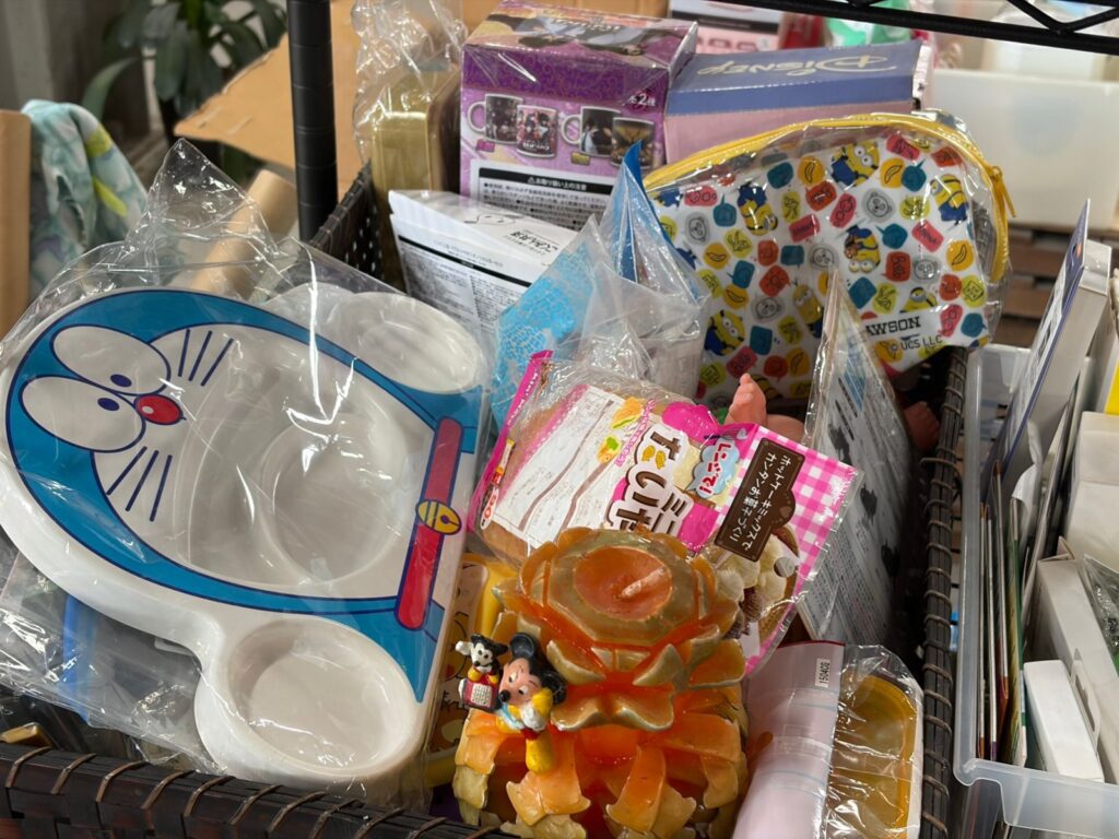 かごの中に、キャラクターの子ども用食器やポーチ、マグカップなどの子ども向けグッズが入っている。