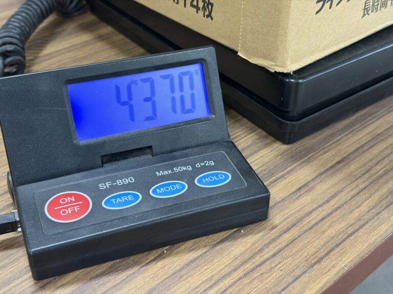 受付の机に置いた台はかり。表示は4.370kg。はかりの上に段ボール箱が載っている。